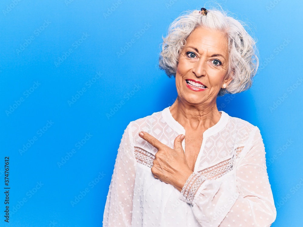 Senior grey-haired woman wearing casual clothes smiling cheerful pointing with hand and finger up to the side