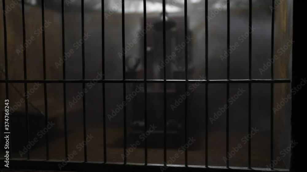 Execution concept. Death penalty electric chair miniature in selective focus inside old prison. Old prison bars cell lock. Creative artwork decoration. Electric chair scale model in the dark Execution concept. Death penalty electric chair miniature in selective focus inside old prison. Old prison bars cell lock. Creative artwork decoration. Electric chair scale model in the dark