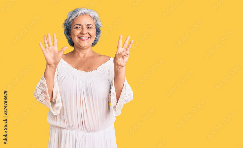 Senior woman with gray hair wearing bohemian style showing and pointing up with fingers number eight while smiling confident and happy. Senior woman with gray hair wearing bohemian style showing and pointing up with fingers number eight while smiling confident and happy.