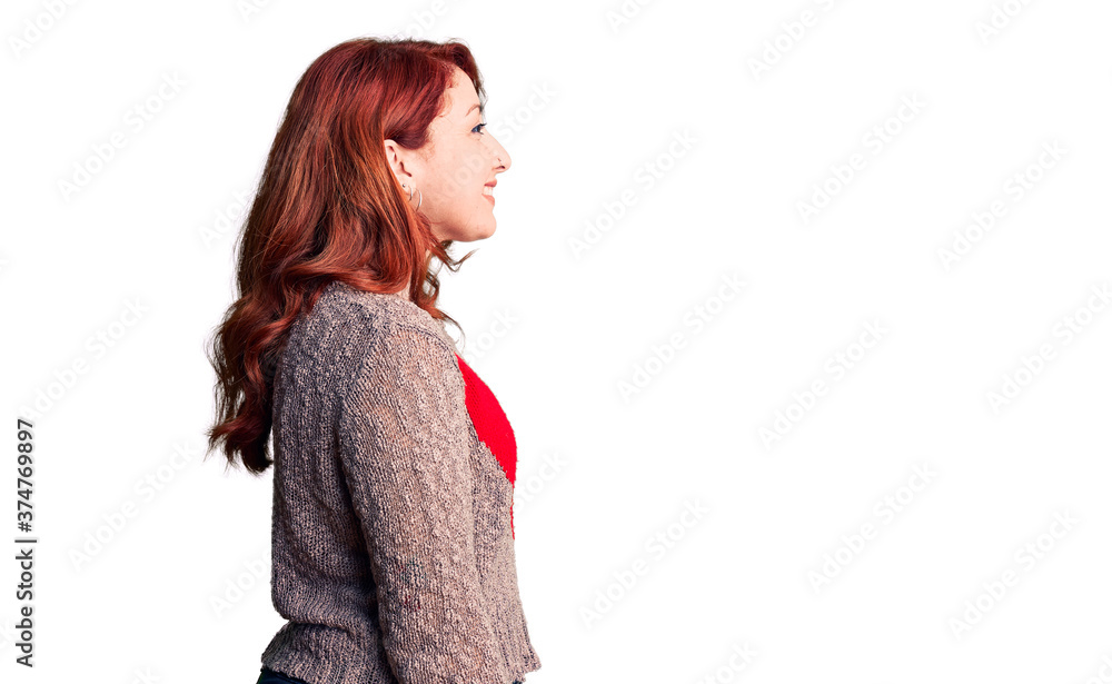 Young beautiful redhead woman wearing casual heart sweater looking to side, relax profile pose with natural face with confident smile. Young beautiful redhead woman wearing casual heart sweater looking to side, relax profile pose with natural face with confident smile.