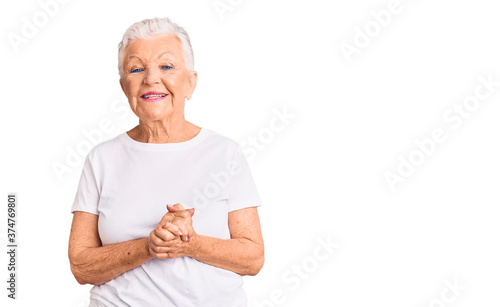 Senior beautiful woman with blue eyes and grey hair wearing casual white tshirt with hands together and crossed fingers smiling relaxed and cheerful. success and optimistic