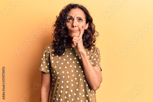 Middle age beautiful woman wearing casual t shirt thinking concentrated about doubt with finger on chin and looking up wondering