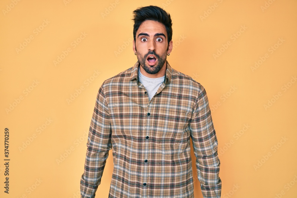 Handsome hispanic man with beard wearing casual clothes afraid and shocked with surprise expression, fear and excited face.