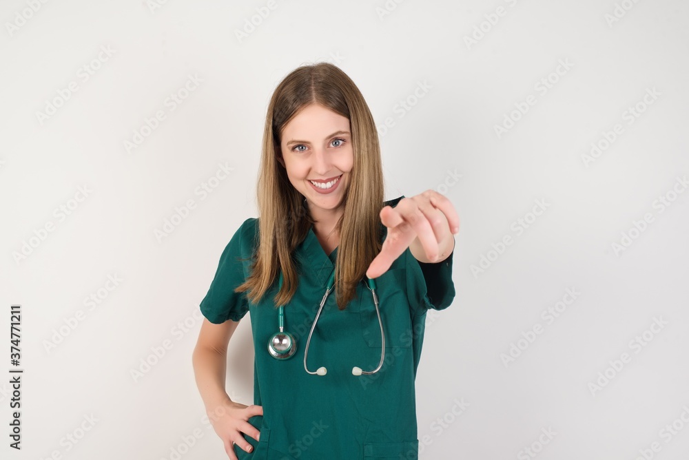 Female doctor wearing a green scrubs and stethoscope pointing at camera with a satisfied, confident, friendly smile, choosing you Female doctor wearing a green scrubs and stethoscope pointing at camera with a satisfied, confident, friendly smile, choosing you