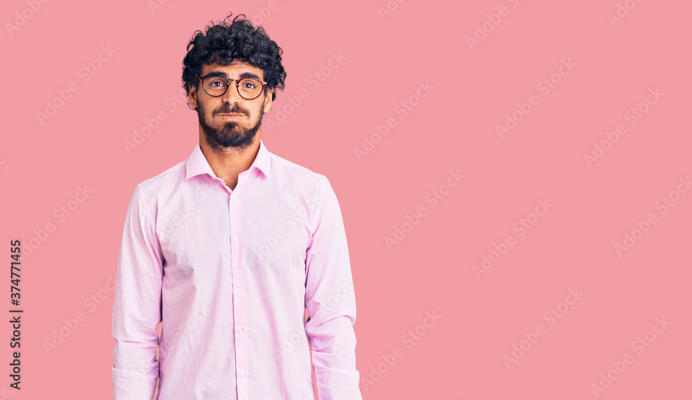 Handsome young man with curly hair and bear wearing business clothes puffing cheeks with funny face. mouth inflated with air, crazy expression. Handsome young man with curly hair and bear wearing business clothes puffing cheeks with funny face. mouth inflated with air, crazy expression.