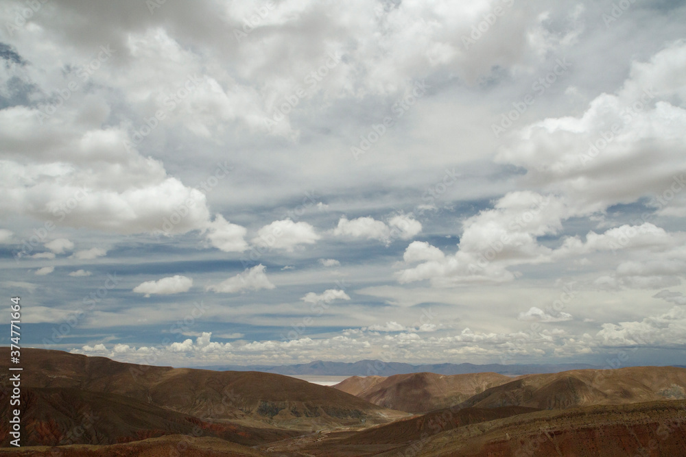 Desert landscape. Aerial view of the brown  arid mountains and valley under a beautiful cloudy sky.