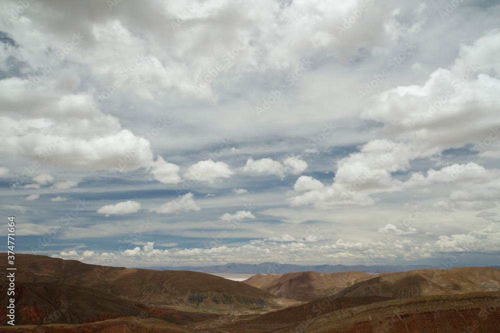 Desert landscape. Aerial view of the brown arid mountains and valley under a beautiful cloudy sky. Desert landscape. Aerial view of the brown arid mountains and valley under a beautiful cloudy sky.