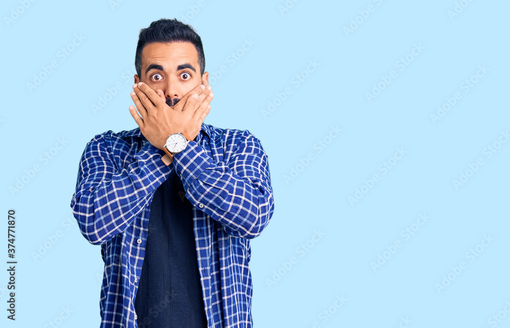 Young hispanic man wearing casual clothes shocked covering mouth with hands for mistake. secret concept. Young hispanic man wearing casual clothes shocked covering mouth with hands for mistake. secret concept.