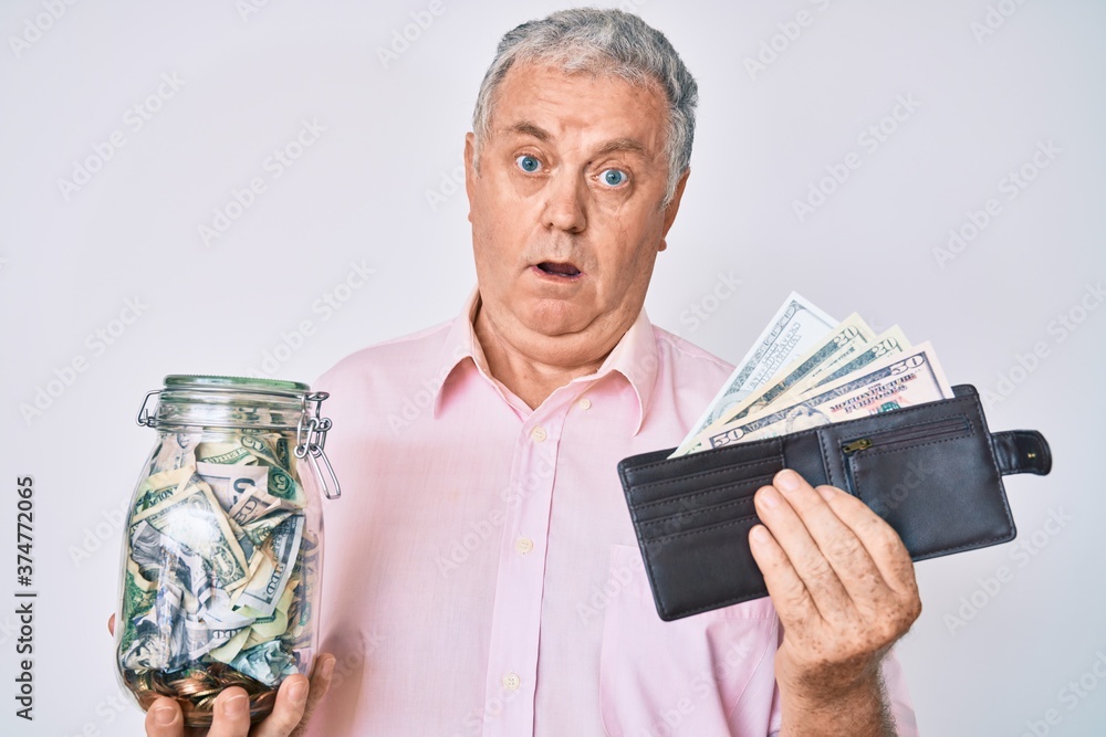 Senior grey-haired man holding wallet with dollars and jar with savings clueless and confused expression. doubt concept. Senior grey-haired man holding wallet with dollars and jar with savings clueless and confused expression. doubt concept.