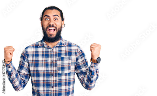 Young arab man wearing casual clothes celebrating surprised and amazed for success with arms raised and open eyes. winner concept.