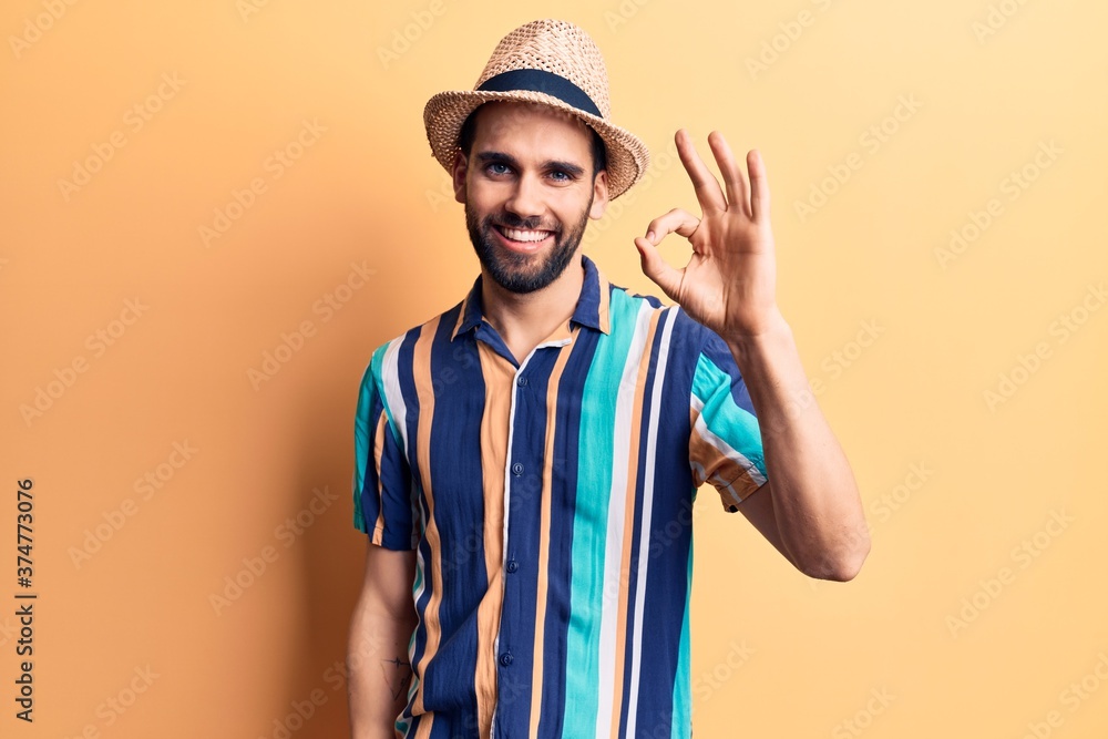 Young handsome man with beard wearing summer hat and shirt smiling positive doing ok sign with hand and fingers. successful expression. Young handsome man with beard wearing summer hat and shirt smiling positive doing ok sign with hand and fingers. successful expression.