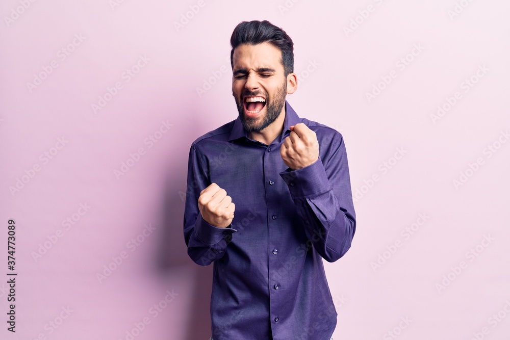 Young handsome man with beard wearing casual shirt celebrating surprised and amazed for success with arms raised and eyes closed. winner concept. Young handsome man with beard wearing casual shirt celebrating surprised and amazed for success with arms raised and eyes closed. winner concept.