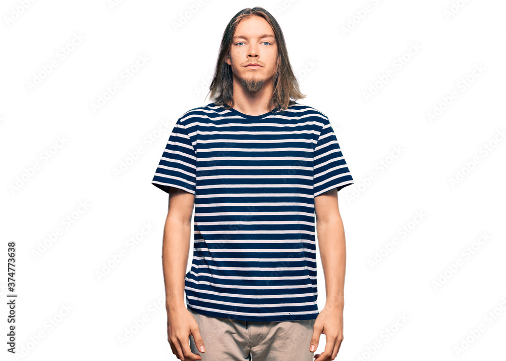 Obraz premium Handsome caucasian man with long hair wearing casual striped t-shirt relaxed with serious expression on face. simple and natural looking at the camera.