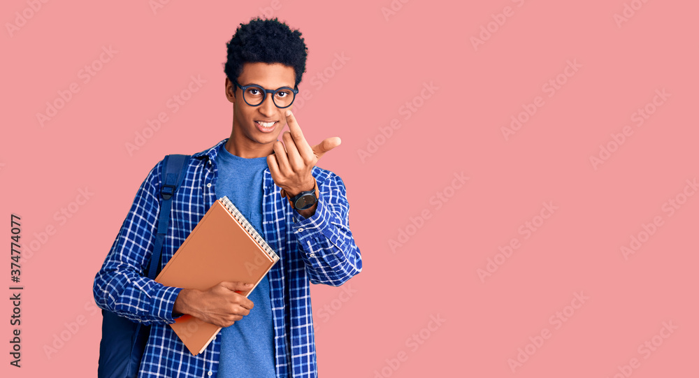 Young african american man wearing student backpack holding book beckoning come here gesture with hand inviting welcoming happy and smiling Young african american man wearing student backpack holding book beckoning come here gesture with hand inviting welcoming happy and smiling
