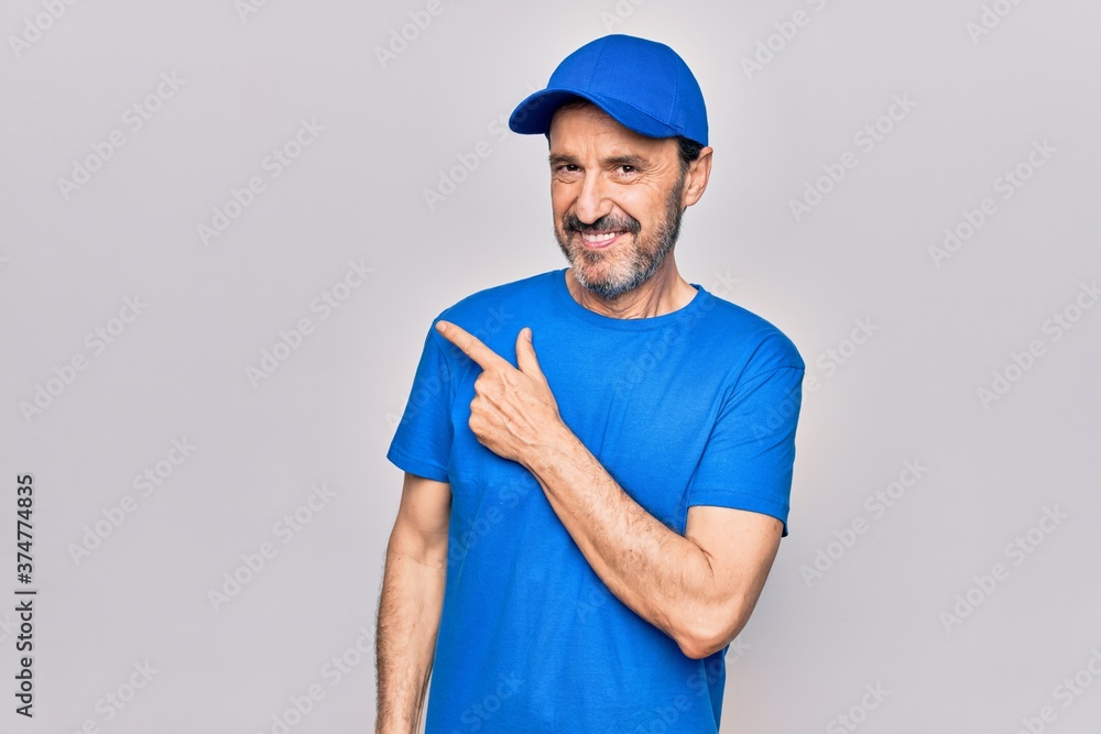 Middle age handsome deliveryman wearing cap standing over isolated white background smiling cheerful pointing with hand and finger up to the side Middle age handsome deliveryman wearing cap standing over isolated white background smiling cheerful pointing with hand and finger up to the side
