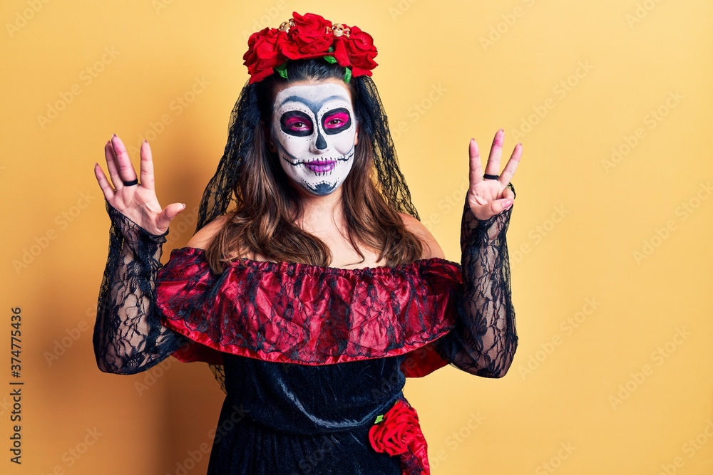 Young woman wearing day of the dead costume over yellow showing and pointing up with fingers number eight while smiling confident and happy. Young woman wearing day of the dead costume over yellow showing and pointing up with fingers number eight while smiling confident and happy.