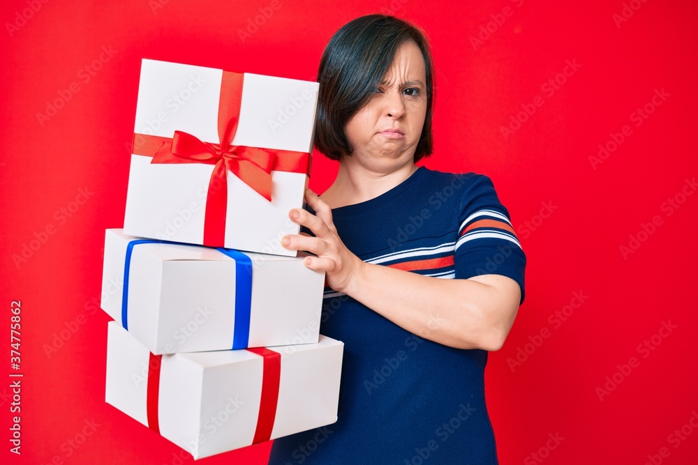 Brunette woman with down syndrome holding gifts skeptic and nervous, frowning upset because of problem. negative person. Brunette woman with down syndrome holding gifts skeptic and nervous, frowning upset because of problem. negative person.