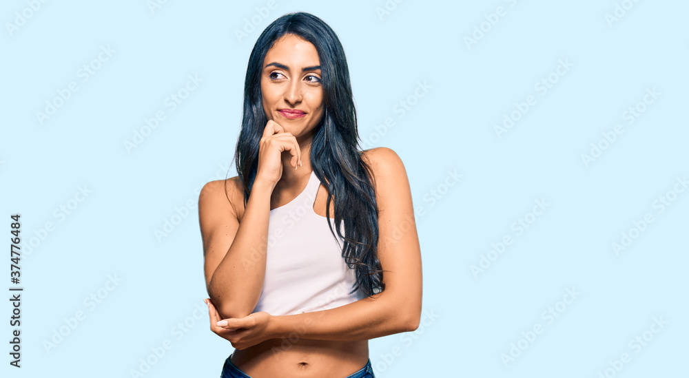 Fototapeta premium Beautiful hispanic woman wearing casual clothes with hand on chin thinking about question, pensive expression. smiling and thoughtful face. doubt concept.