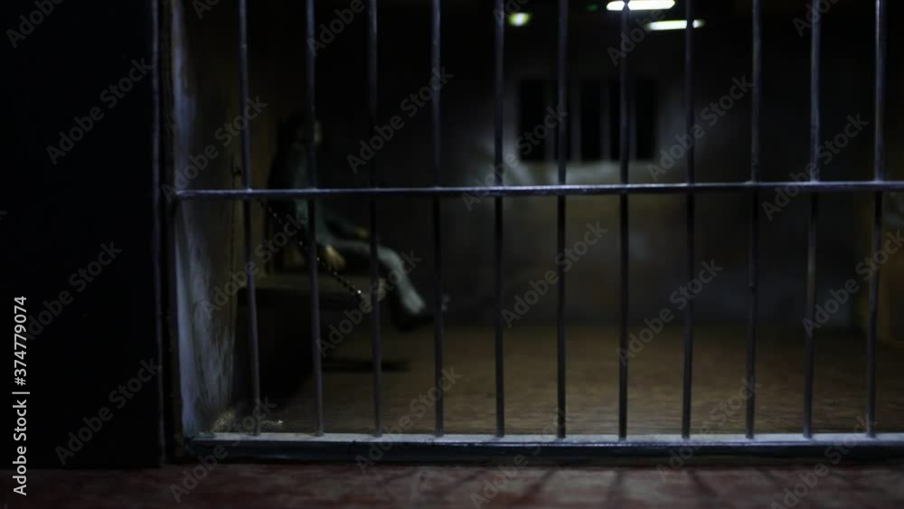 Man in prison man behind bars concept. Old dirty grunge prison miniature. Dark prison interior creative decoration with handcuffs. Selective focus Man in prison man behind bars concept. Old dirty grunge prison miniature. Dark prison interior creative decoration with handcuffs. Selective focus