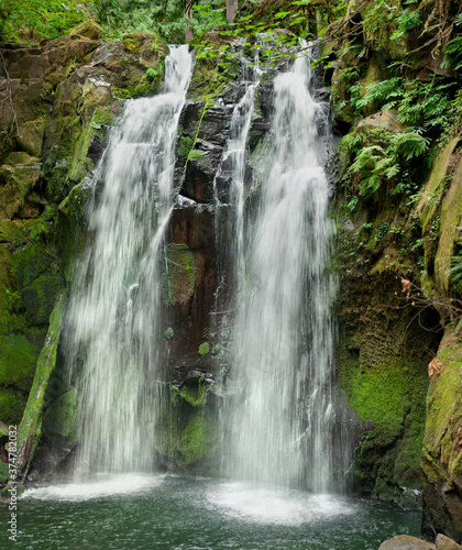  Cascading waterfall with mossy rocks in closeup vertical panoramic view 