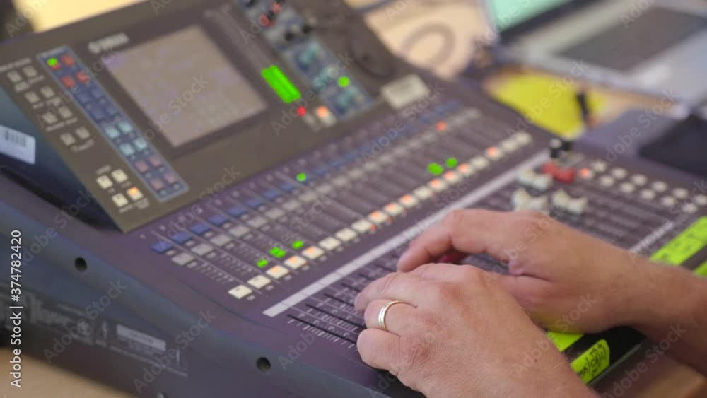 Sound engineer moves sliders on digital audio mixer in the control desk of a recording studio production room. Sound engineer moves sliders on digital audio mixer in the control desk of a recording studio production room.