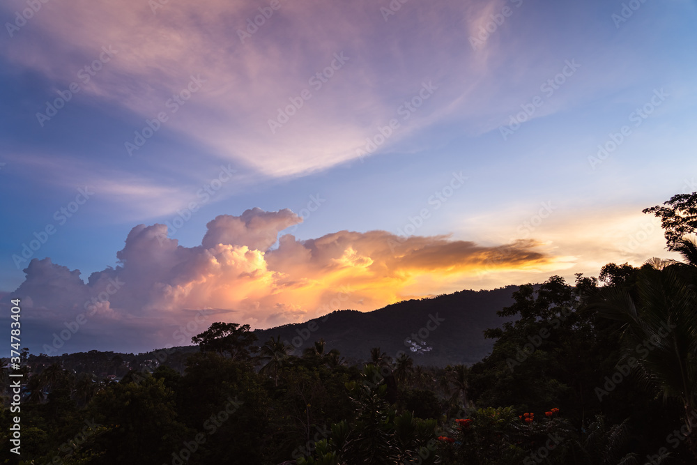 Spectacular sunset sky over valley with trees, city and mountains. View from the top.