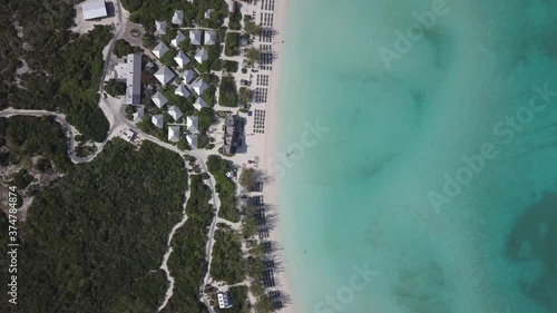 Flying over beach resort on tropical island with beatific sandy beach and crystal clear water bay. Droning over paradise passing slowly and steady.