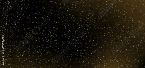 Gold glitter on black background. Many golden dots particles in darkness.