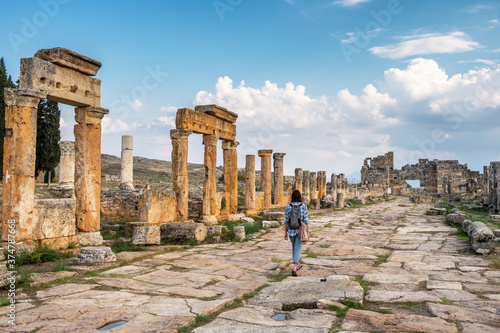 Unidentified female tourist walks through the ruins of the antique city Hierapolis, Pamukkale, Turkey photo