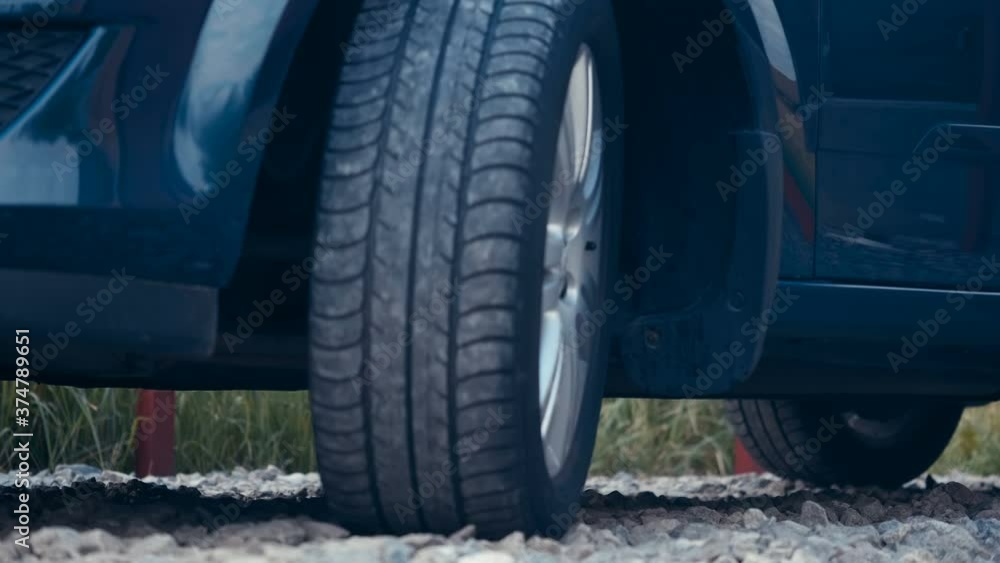 The blue car starts and drives slowly, shiny silver rims shine in the light, reflections on the shiny body of the car The blue car starts and drives slowly, shiny silver rims shine in the light, reflections on the shiny body of the car