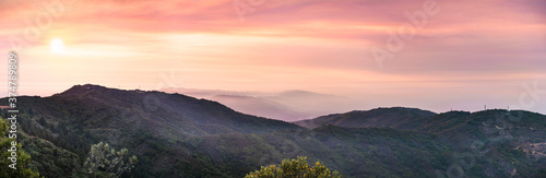Fototapeta Naklejka Na Ścianę i Meble -  Panoramic sunset views in Santa Cruz mountains; Smoke from the nearby burning wildfires, visible in the air and covering the mountain ridges and valleys; South San Francisco Bay Area, California