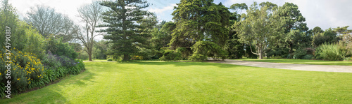 Fotografia Panoramic view of a large formal garden landscaping with well-tended neat lawn and a variety of trees, flower beds and walkway