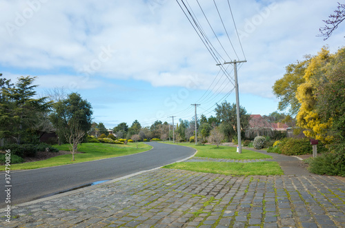 An Australian suburban quiet neighbourhood street with electricity poles along the road. Werribee, VIC Australia.