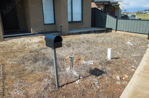 Photography A neglected dry front yard with bare dirt and dead weeds of a residential house in an Australian neighbourhood