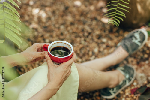 Woman sitting on the ground and hand hold cup of coffee