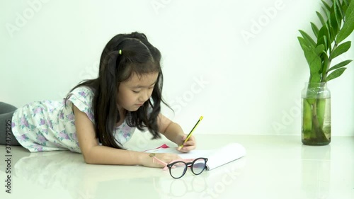 asian child student or kid girl smile writing drawing and enjoy doing homework or happy read learn and training write on paper 