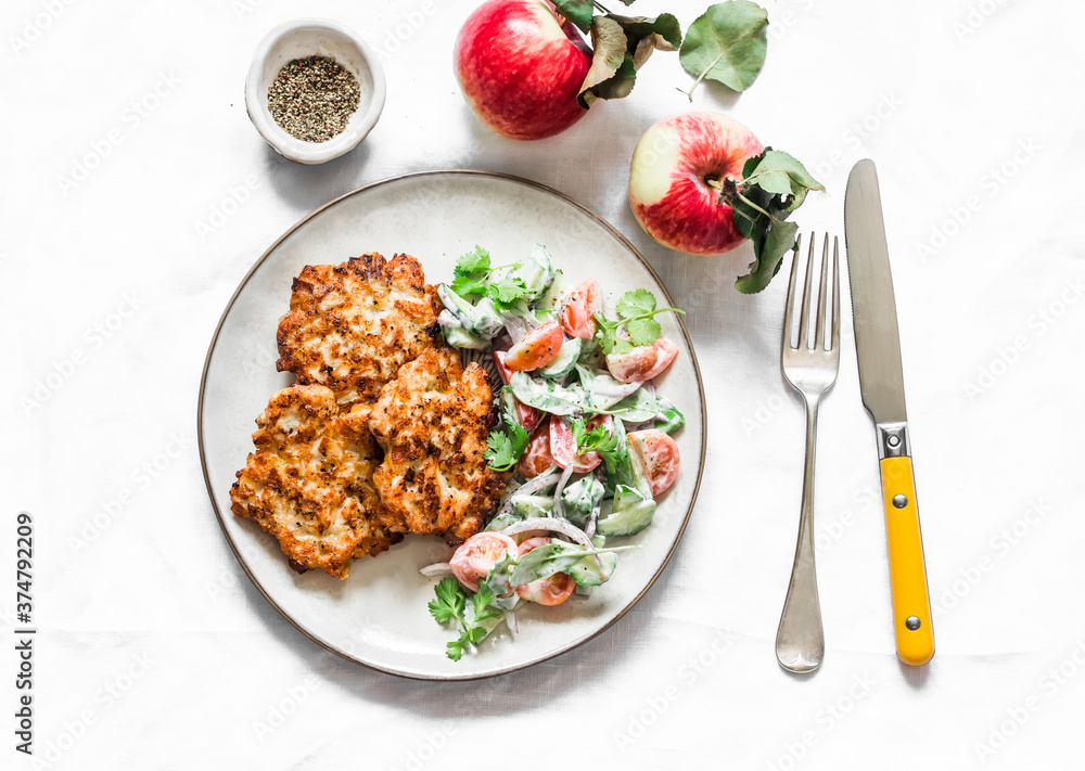 Delicious chicken fillet, apple fritters and fresh vegetables yogurt dressing salad on a light background, top view