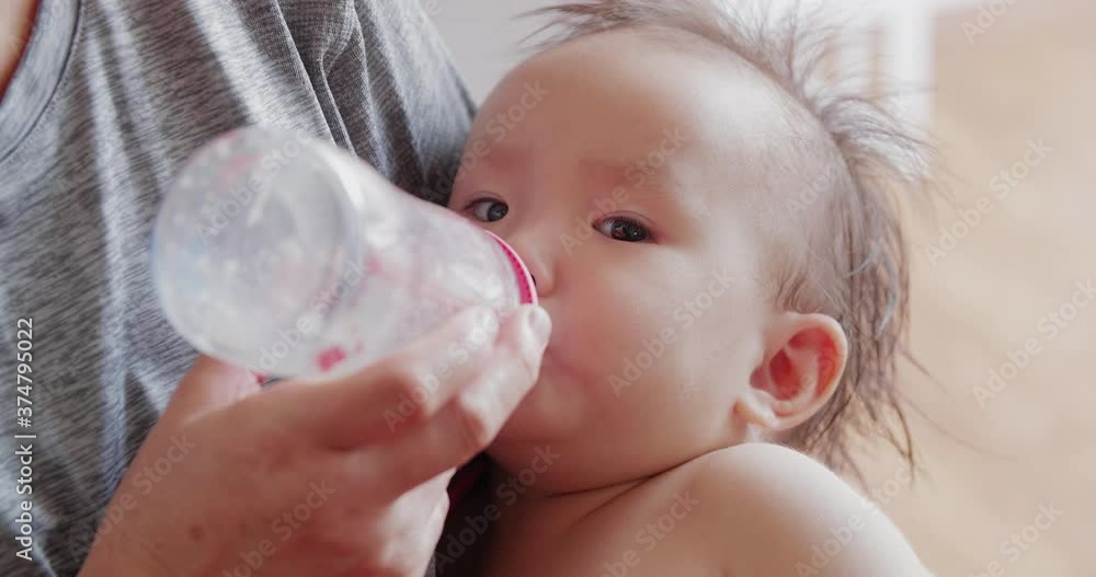 Close up of one asian baby girl drinking milk in the parents arm lovely Chinese infant baby eating drinking Close up of one asian baby girl drinking milk in the parents arm lovely Chinese infant baby eating drinking
