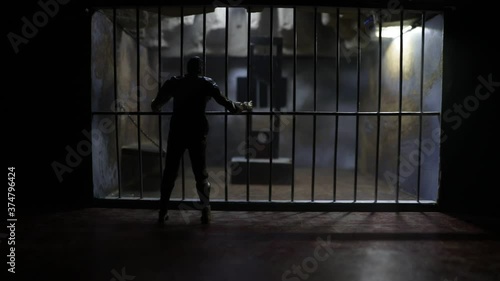 Execution concept. Death penalty guillotine miniature inside old prison. Old prison bars cell lock. Man inside jail. Horror view of Guillotine scale model in the dark