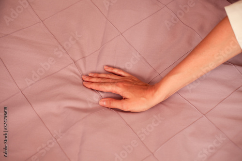 Female hand on the background of a gray bed. Close-up photo