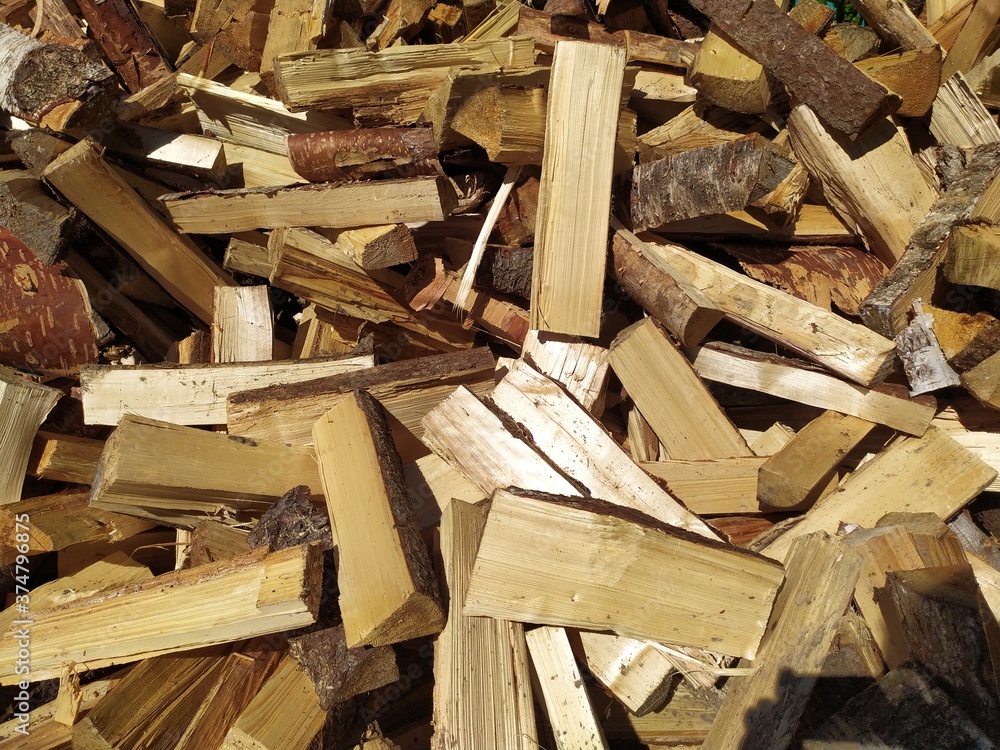 A large pile of chopped wood with an axe in front of the wooden blue house A large pile of chopped wood with an axe in front of the wooden blue house
