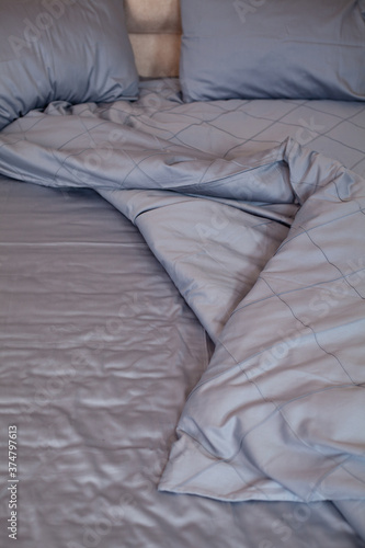 
Unmade empty bed. Bed linen is dark blue.