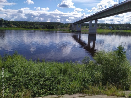 A long high concrete bridge over a wide calm river Suhona ,Russia © Zhanna