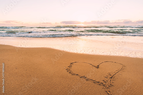heart on the beach handwriting heart shape on sand coastline ocean with sunrise sunset symbols of love
