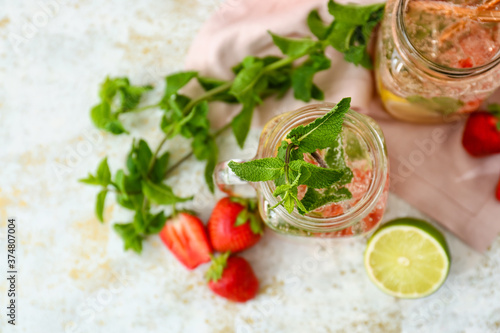 Mason jars of tasty strawberry mojito on light background