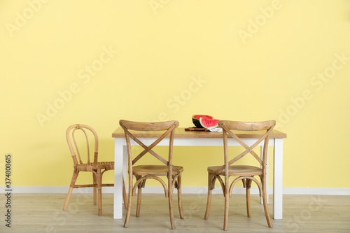 Dining table with watermelon near color wall