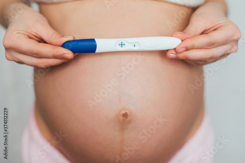a positive pregnancy test in the hands of a pregnant young girl