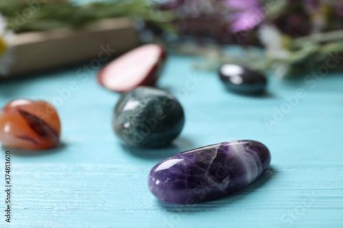 Healing gemstones on light blue wooden table, closeup