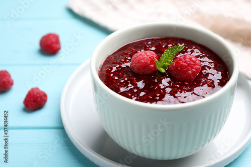 Delicious jam and fresh raspberries on light blue wooden table, closeup