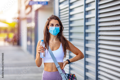 Young fit slim woman in sportswear protection face mask posing during self isolation quarantine. COVID-19 concept to promote stay safe home save lives. Free space for text mockup banner © Dragana Gordic